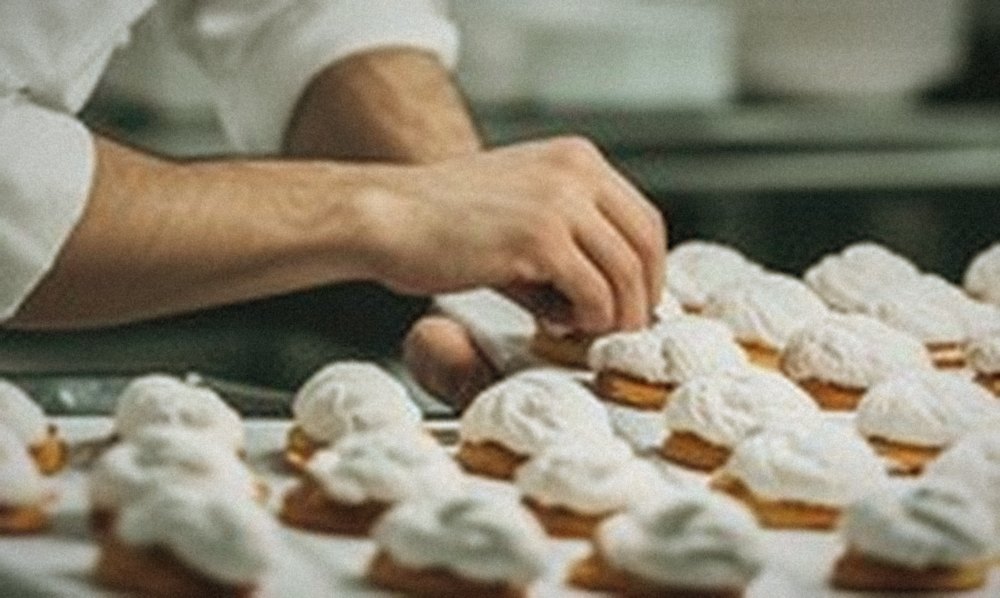 Main d’un pâtissier qui dispose des viennoiseries une à une